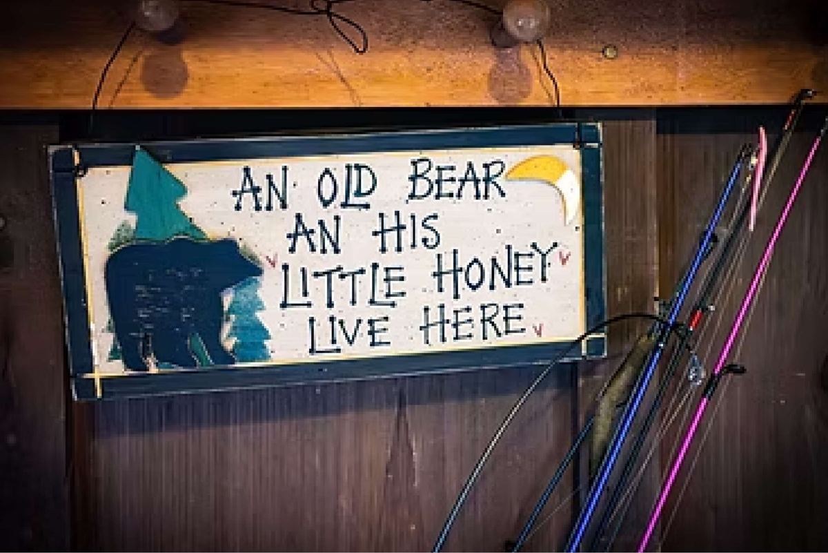 Painted sign: An old bear an his little honey live here