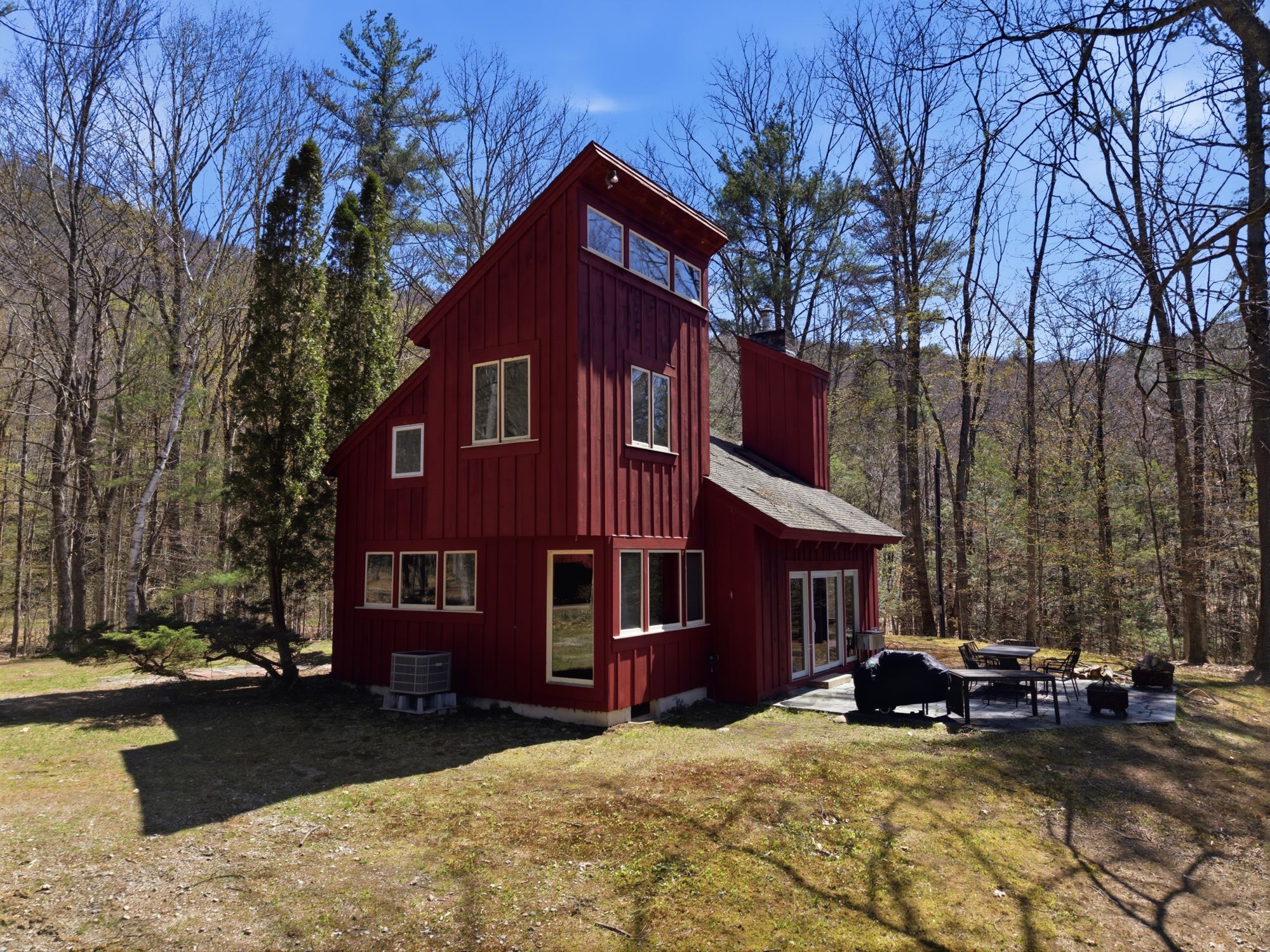 The red Joia Verde chalet in the spring forest, seen from the drone